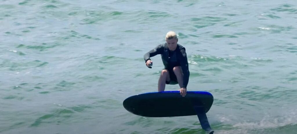 man in wetsuit riding efoil