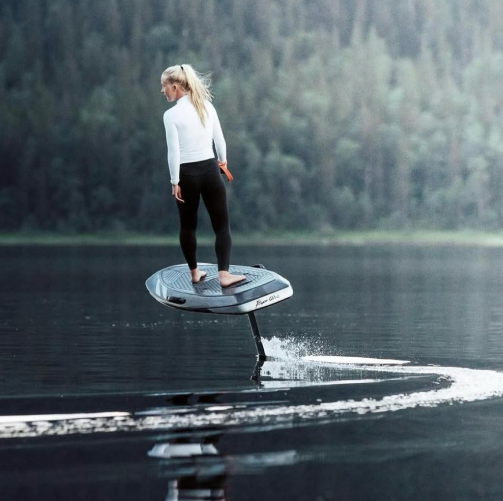 Rider on a Carbon eFoil board gliding across calm lake water, showing lightweight performance and smooth electric hydrofoil control.