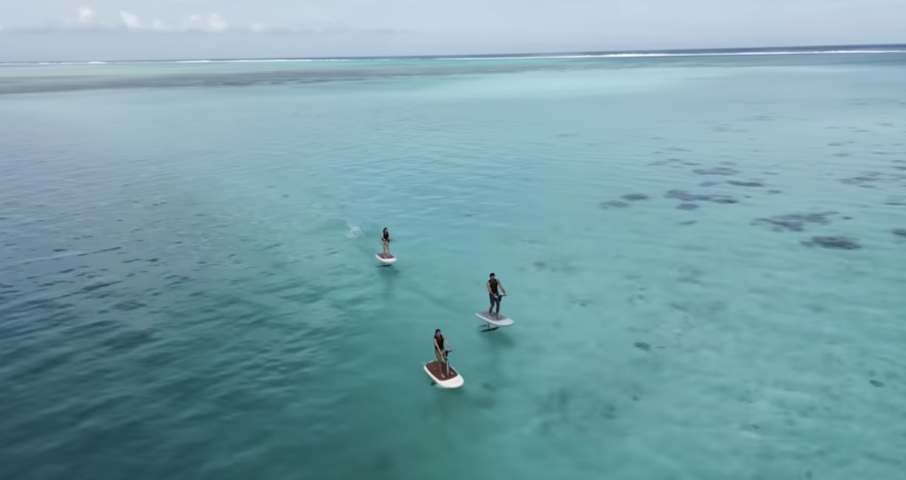 Group of riders using FliteScooter eFoils over clear turquoise water, showcasing beginner-friendly electric foiling for families and shared adventures.