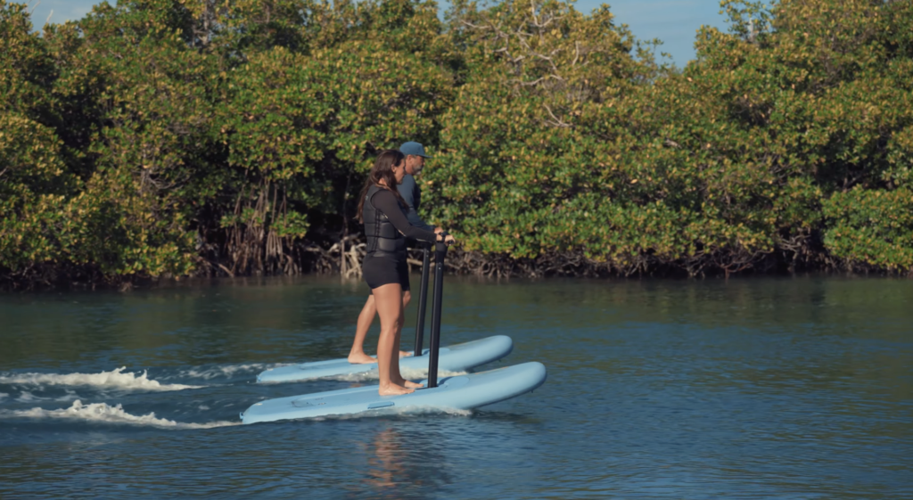 Two riders using FliteScooters with handlebars on calm water
